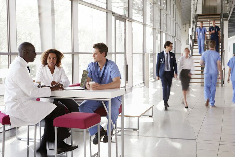 image of hospital corridor with nurses sitting at a table by a window