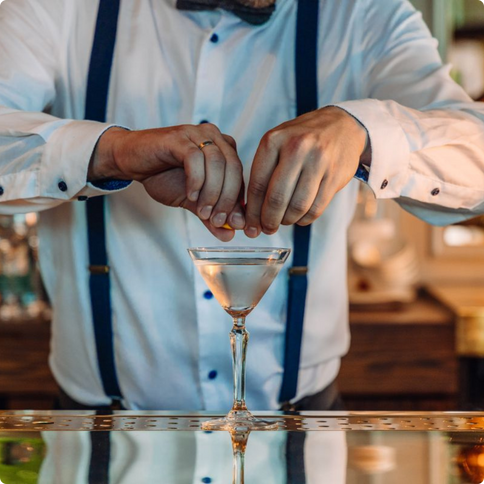 A smartly dressed bartender adding garnish to a martini glass