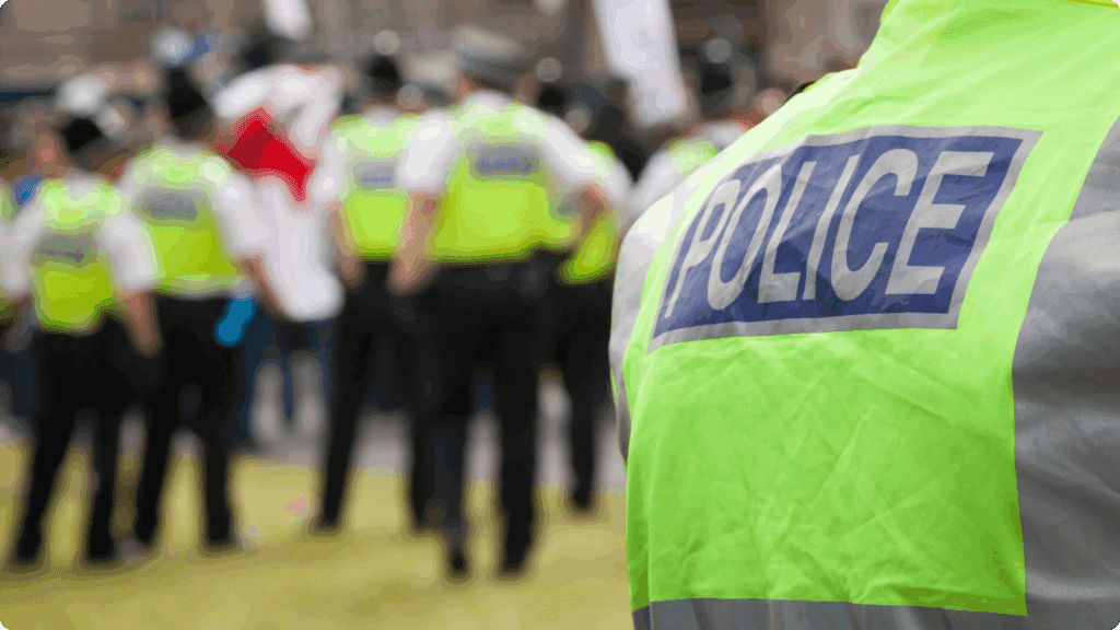 Close up of a police officer's back wearing a hi-viz jacket with more officers out of focus in the background